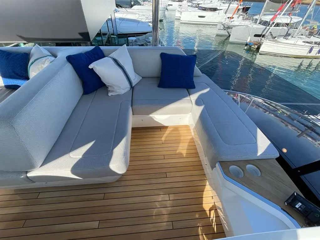 Contemporary yacht seating area with blue and white cushions, wooden deck, and views of boats on the water.